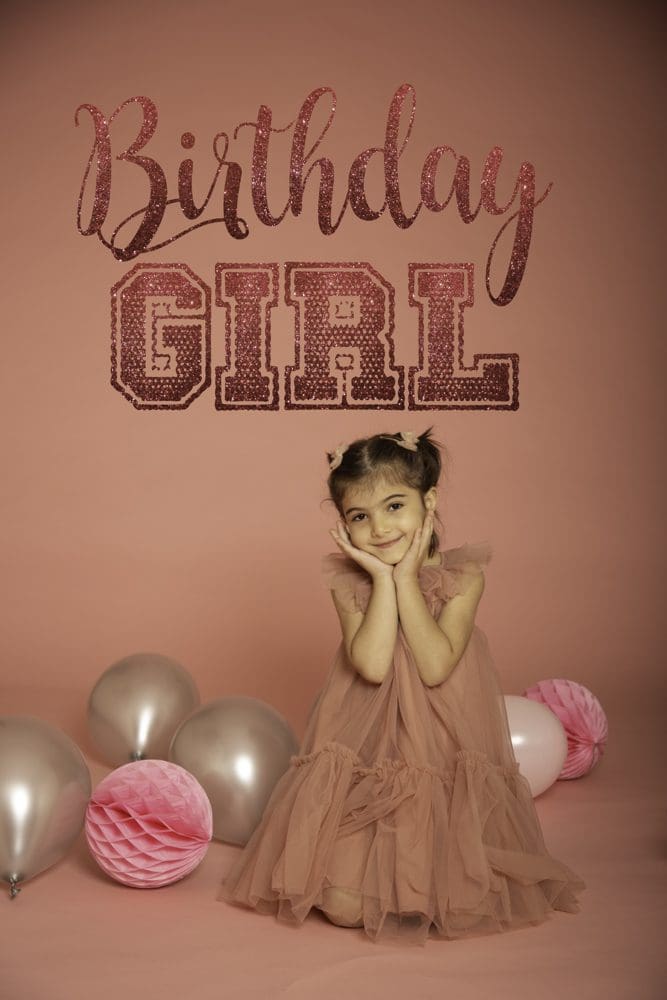 Young girl posing under a “Birthday Girl” sign surrounded by balloons during a studio birthday photoshoot for children in Birmingham.