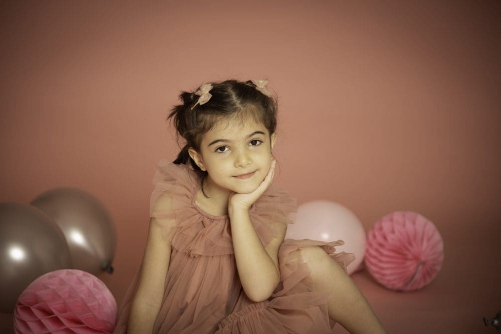 Young girl resting her chin on her hand and smiling during a studio birthday photoshoot for children in Birmingham.