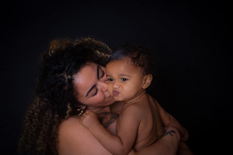 Mother cuddling and kissing her baby during a professional baby photoshoot in Birmingham.