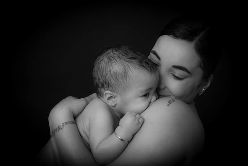 Black and white portrait of a mother cuddling her baby against her shoulder during a professional baby photoshoot in Birmingham.