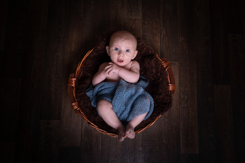 newborn baby portrait in Birmingham photography studio lying in basket viewed from above