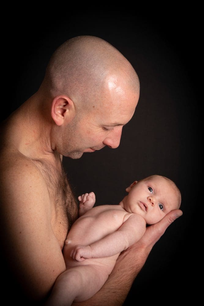newborn baby skin to skin with father in Birmingham newborn photography studio portrait