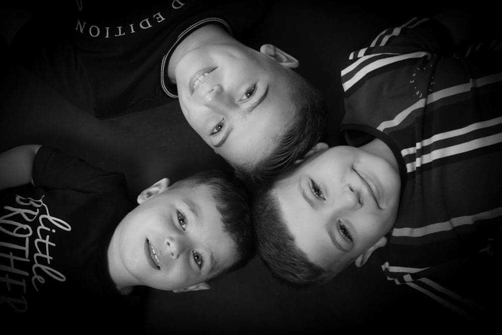 Black and white portrait of three brothers lying head to head during a Birmingham family photoshoot