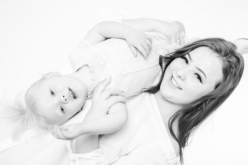 Black and white studio portrait of a mother and daughter lying together during a Birmingham family photoshoot