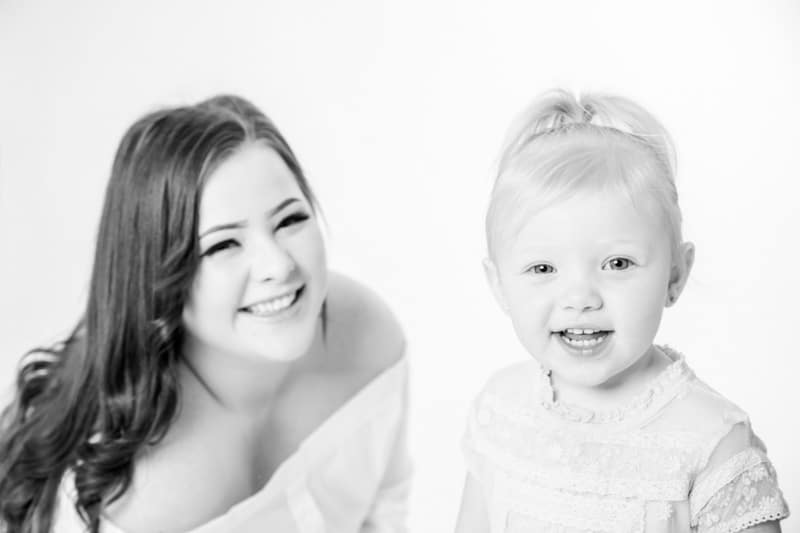 Bright studio portrait of a mother and her young daughter smiling during a Birmingham family photoshoot