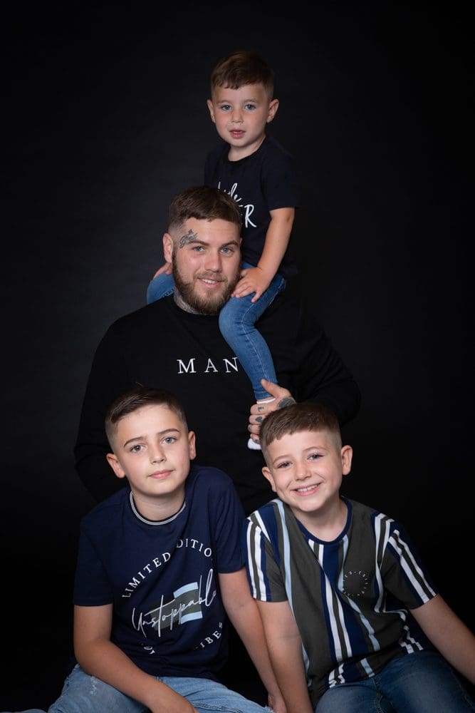 Father posing with his three sons during a relaxed family photoshoot in Birmingham studio
