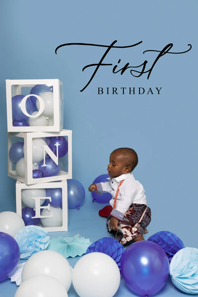 One-year-old child sitting among balloons and personalised blocks during a studio first birthday photoshoot for children in Birmingham.