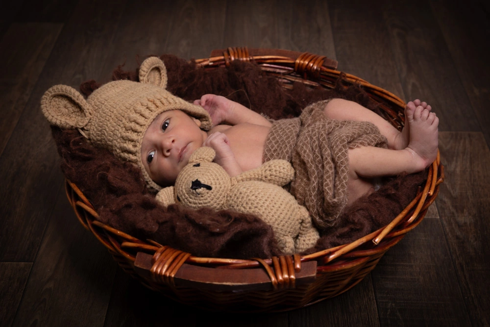 newborn baby portrait in Birmingham photography studio lying in basket with teddy bear