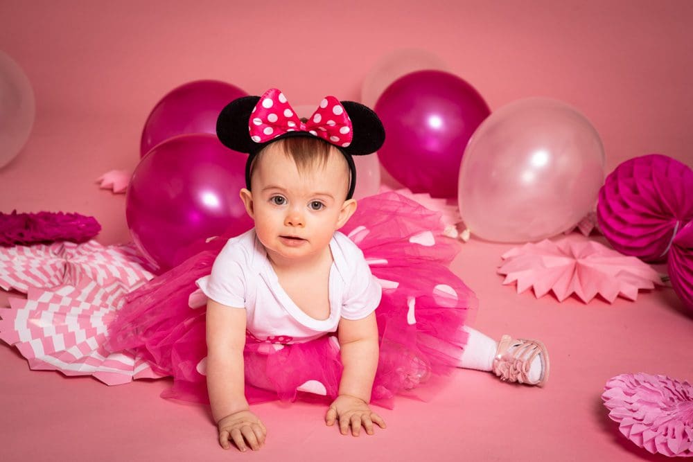 Baby girl wearing a pink tutu and Minnie Mouse ears during a studio birthday photoshoot for children in Birmingham.