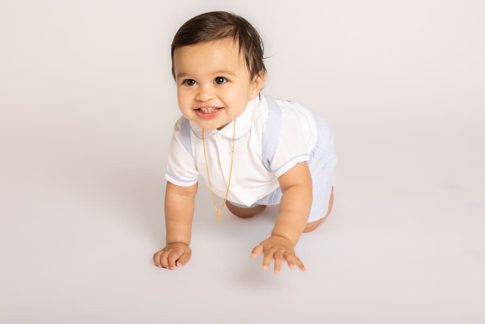 Smiling baby lying on a soft blanket during a professional baby shoot in Birmingham by an experienced newborn photographer.