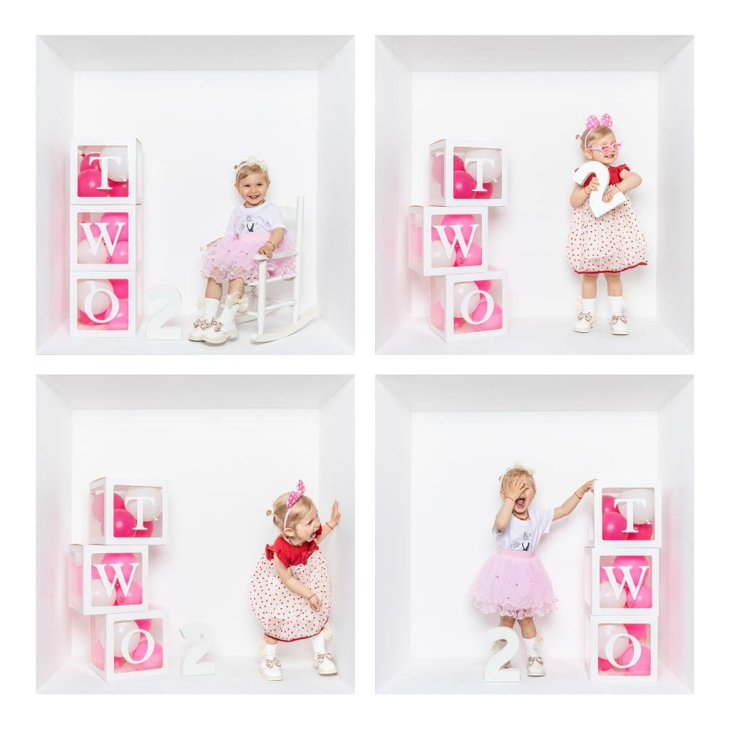 Inside the box photography of a two-year-old girl celebrating her birthday, with pink balloons and number blocks in a white studio box.