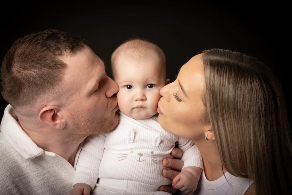 parents kissing baby during Birmingham family photoshoot in photography studio