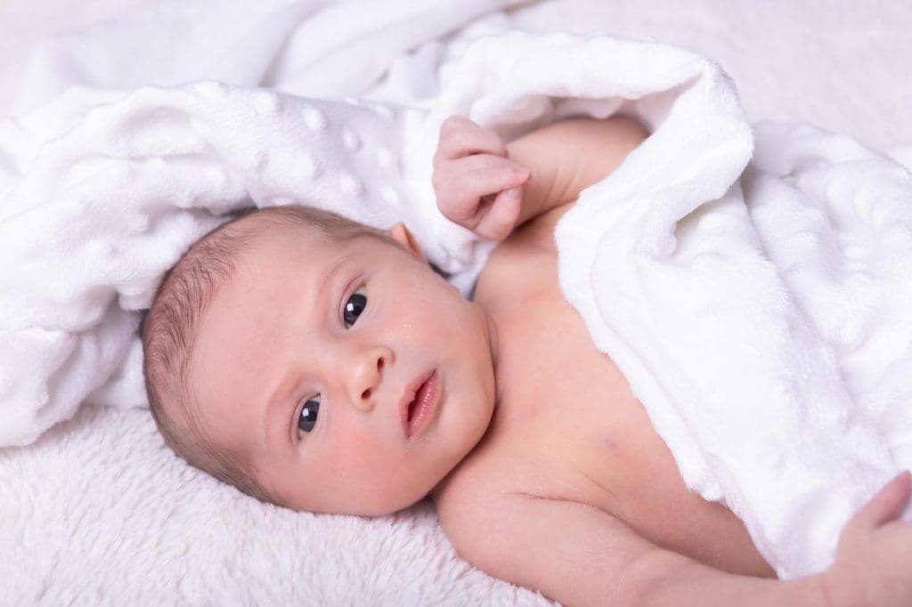 awake newborn baby portrait in Birmingham photography studio lying on soft white blanket