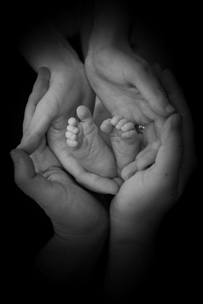 black and white newborn detail portrait in Birmingham photography studio with baby feet in parent hands
